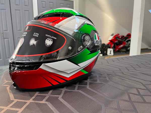 Black, red, white, green new K-6 helmet with Honda race bike in the backgroun