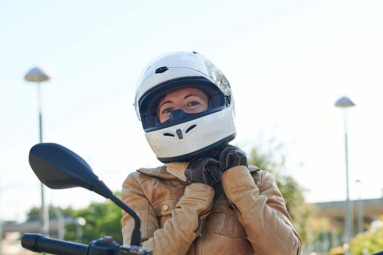 woman adjusting motorcycle helmet to show how long does it take to break in a helmet