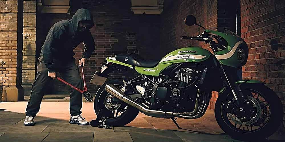 A masked individual holding a chain cutter attempting to steal a securely locked Kawasaki motorcycle. Motorcycle theft is a common issue and its frequency can vary in different cities based on crime rate, motorcycle ownership, and local security measures.