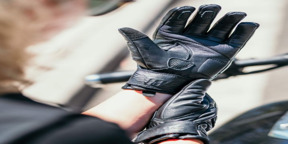 A rider adjusts a pair of short-cuff leather gloves in preparation for a ride.