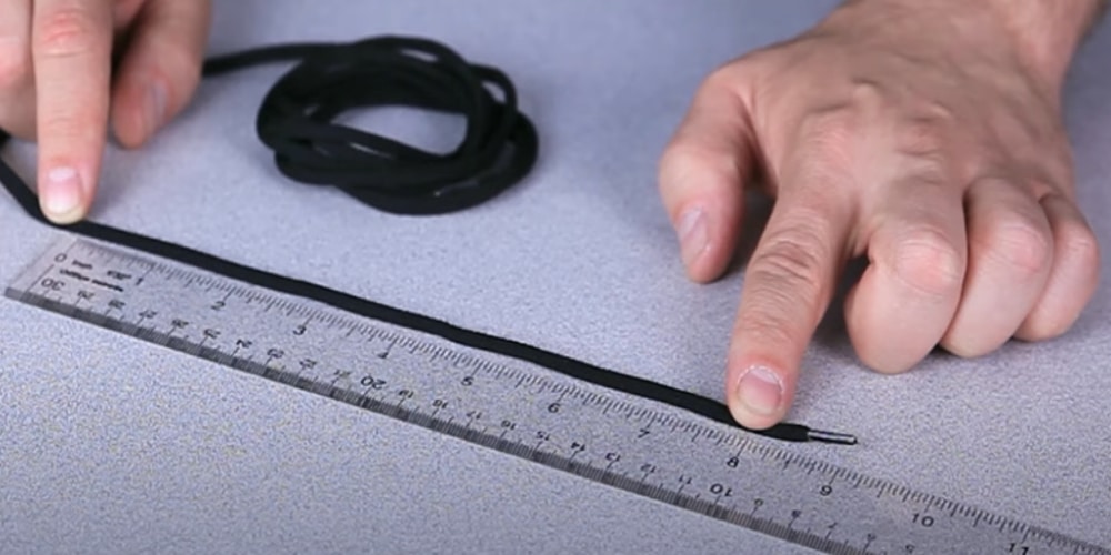 Measuring the marked string against a ruler to determine the actual hand width measurement.