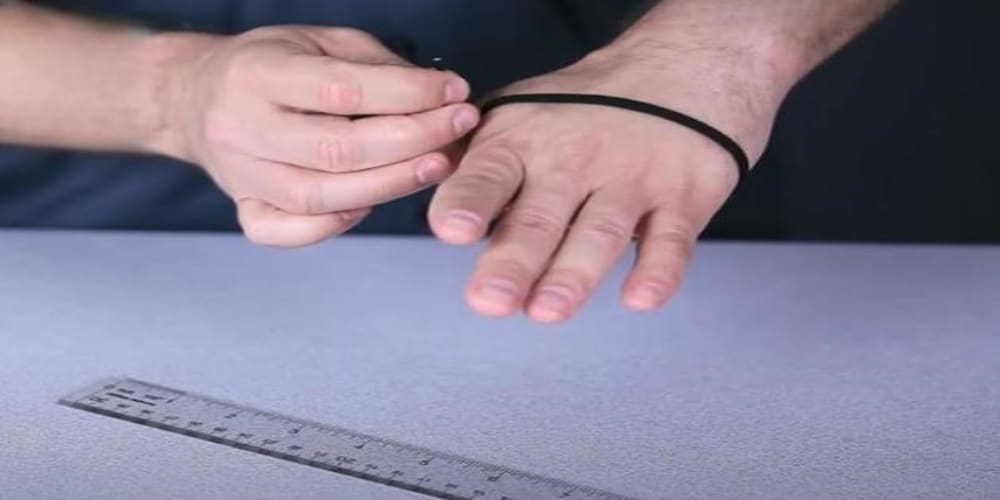 Measuring hand width (circumference) by wrapping a string around the palm just behind the knuckles, excluding the thumb.