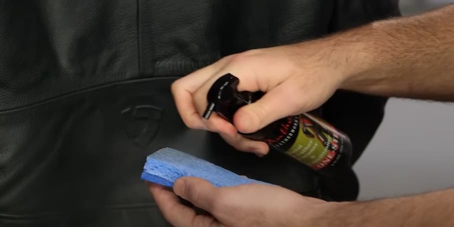 Applying the conditioner by continuously spraying it onto a blue sponge.