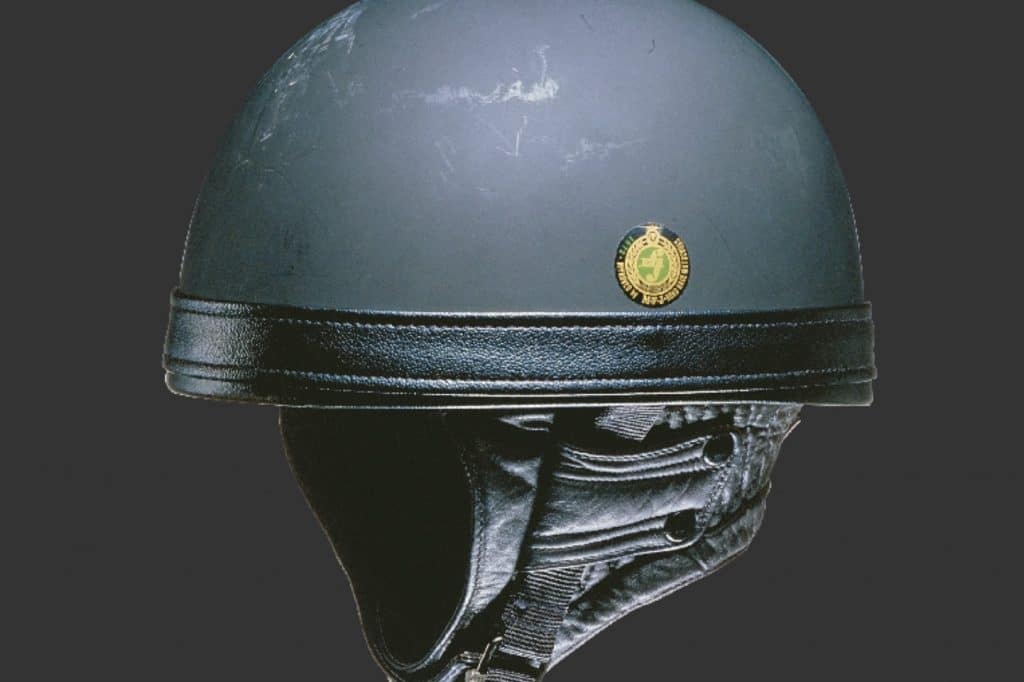 A Shoei black and gray pudding-bowl-style helmet with leather and textile chinstrap and a logo on the side with 1972 among Japanese inscriptions