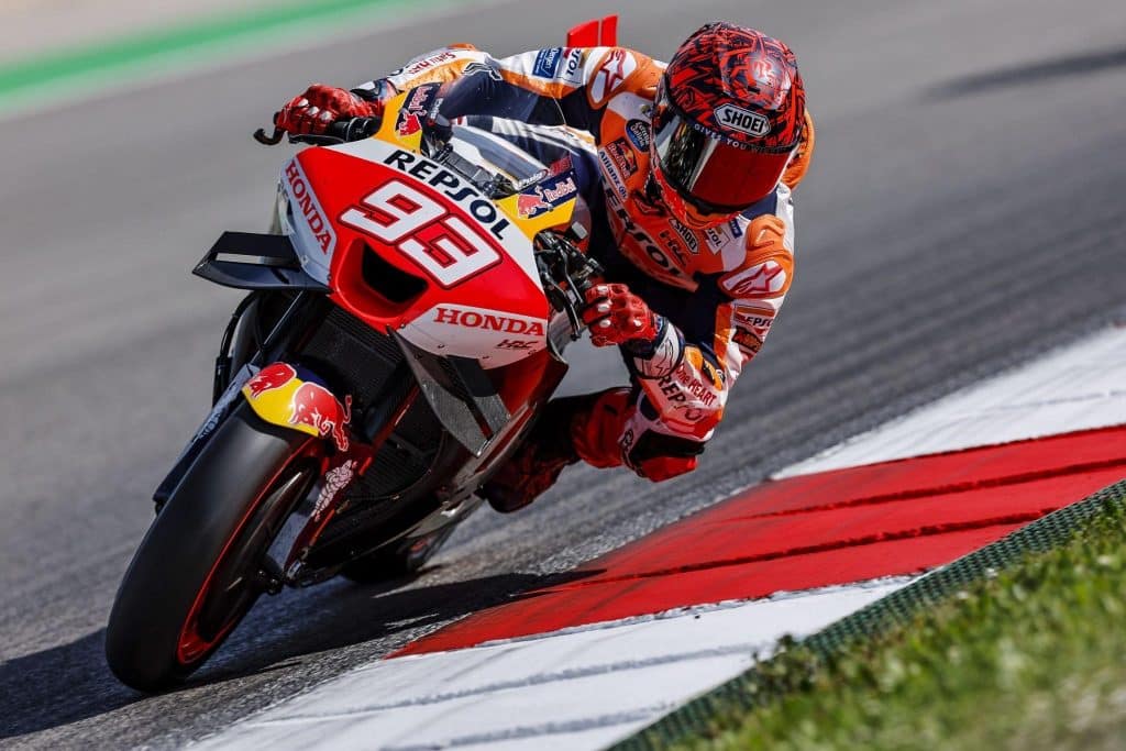 Marc Marquez stretching his limbs on the racy Honda RC213V in preparation for his return to action at Le Mans on May 12-14, 2023, while wearing the new Shoei X-Fifteen Marquez Dazzle helmet.