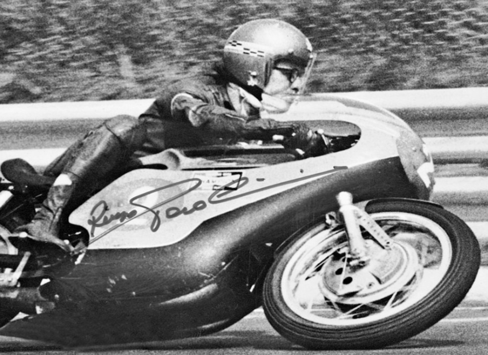 Renzo "Paso" Pasolini, wearing the AGV Jet helmet, leans on a corner as he approaches the finish line. He didn’t abandon his beloved Jet for a full-face AGV model until the 1970s.