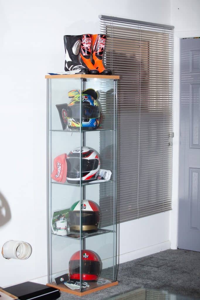 From the bottom up, one of my helmet collections in my Maryland office showcases Niki Lauda's AGV X1, Giacomo Agostini's AGV X3000, Wayne Rainey's AGV Quasar, and Valentino Rossi's AGV Pista GP R. Positioned at the top are AGVSPORT’s motorcycle riding boots.
