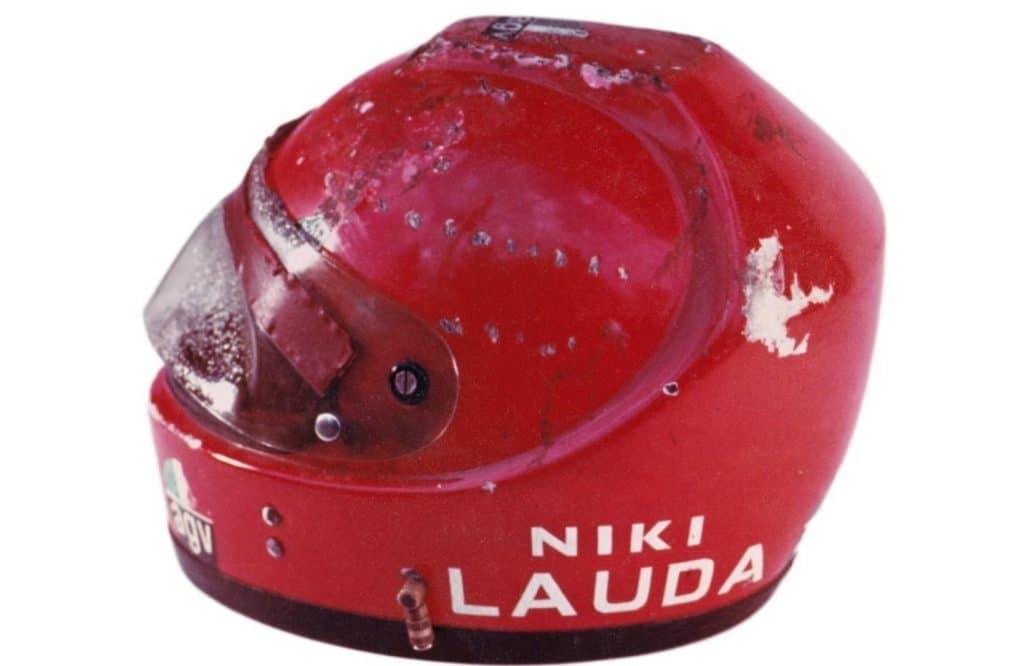 Niki Lauda's customized helmet, unmistakably bearing the brunt of a crash result, prominently exhibits signs of damage on the face shield.
