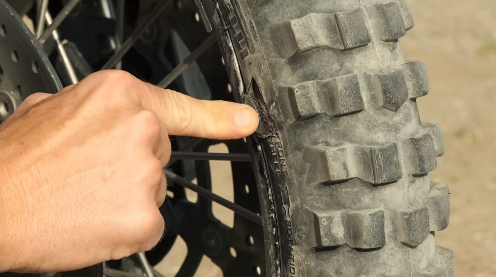 Inspecting a nasty cut on the sidewall of a 21” front Pirelli tire of a Yamaha T7. The thin tires give the bike its off-road super power, but they are not indestructible. It is always wise to carry a tube and thick tire patches, even for tubeless tires, in case this happens.