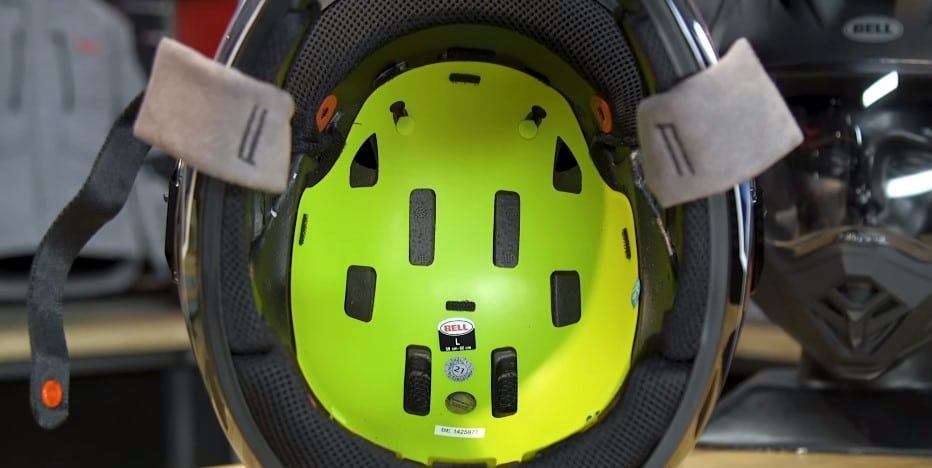 Interior view of the Bell MX-9 Adventure MIPS helmet, revealing the vibrant yellow MIPS layer. Observe the presence of size and serial number stickers.