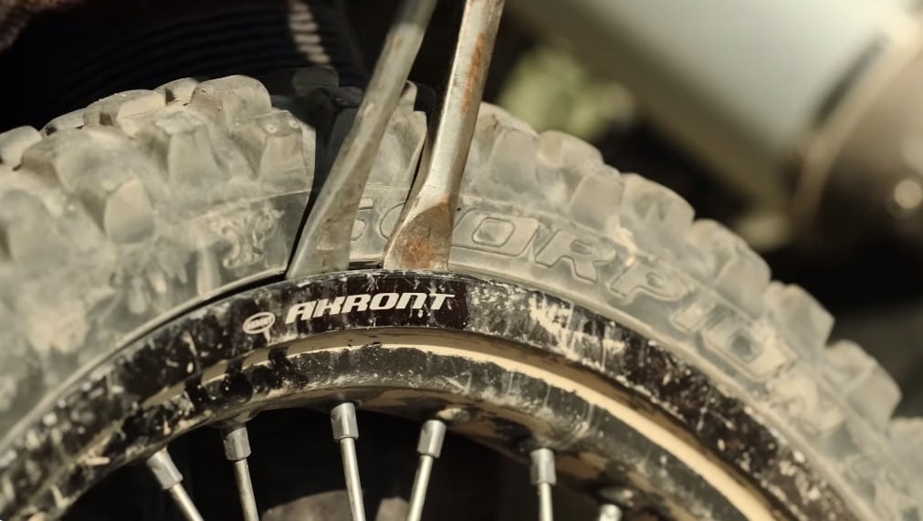 Plying of the rubber bead of a scorpion off-road tire to unseat it from the rim and expose the inner tubes for repair. Proper adventure inner tubes are made of natural rubber, which is thicker and more pliable than the thin budget ones that your bike first ships out with.