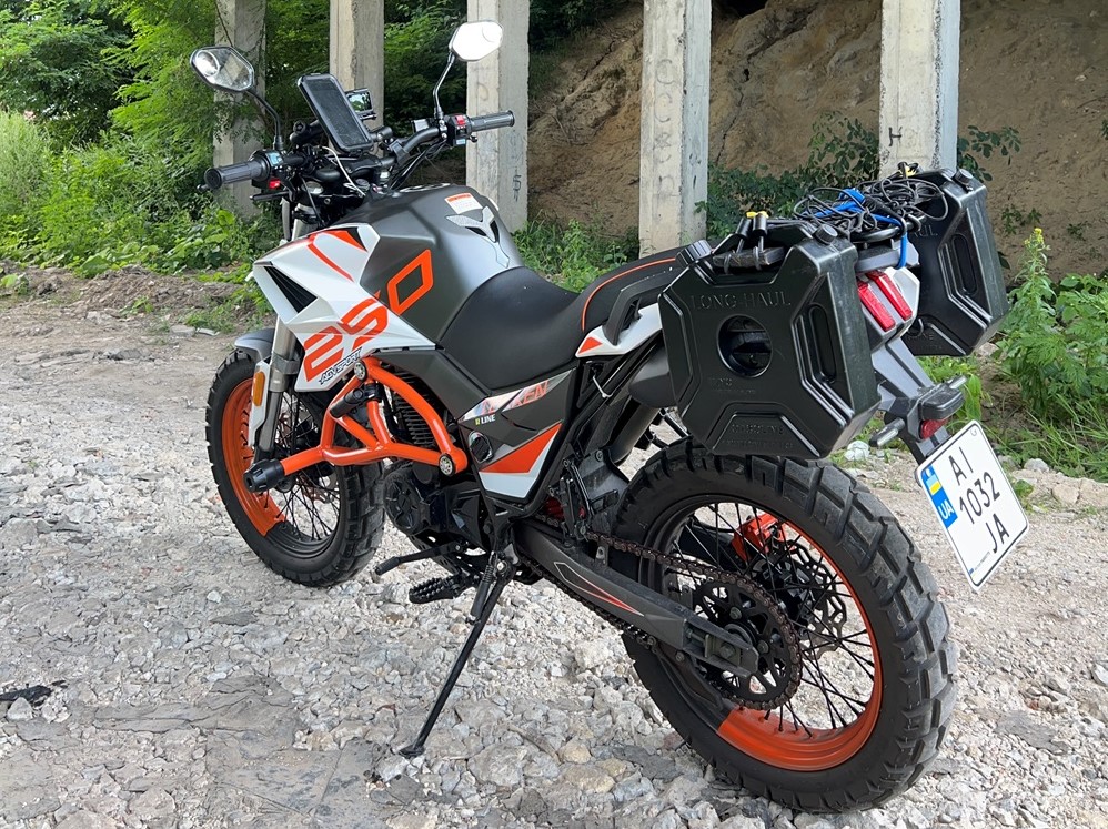 Tekken 250 adventure touring motorcycle stands tall on a semi-challenging Ukrainian road. Featuring a handlebar phone mount and two small auxiliary fuel tanks at the rear, ready for any fuel emergency during long-distance rides.