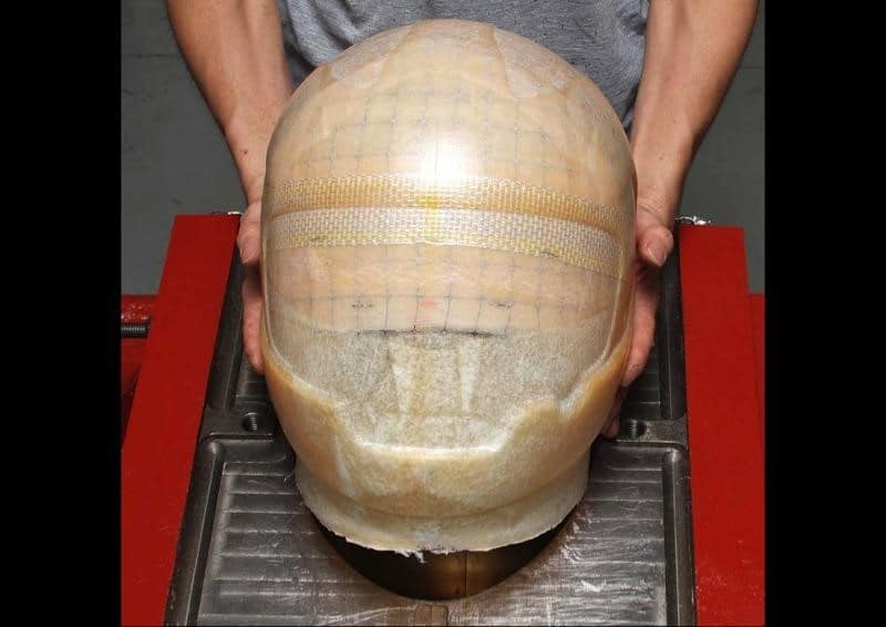 At this stage, the freshly molded shell emerges from the mold, revealing its raw form. It is now ready to undergo the precise artistry of the laser cutter. It’s worth noting that any staples used to secure specific fiberglass layers are strategically placed within the eyeport area, which is destined to be cut out during this process.