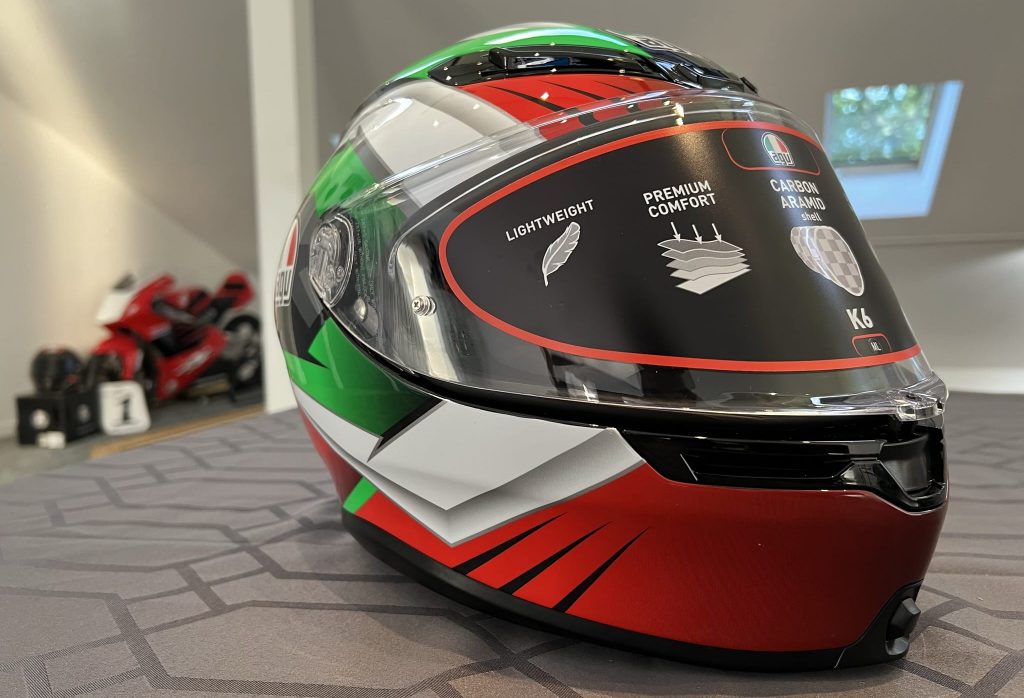 The AGV K6 S Excite Camo/Italy graphics Hi-Viz helmet displayed in my Maryland office. With its eye-catching red, white, and green color scheme, it ensures high visibility and a strategically advantageous profile.