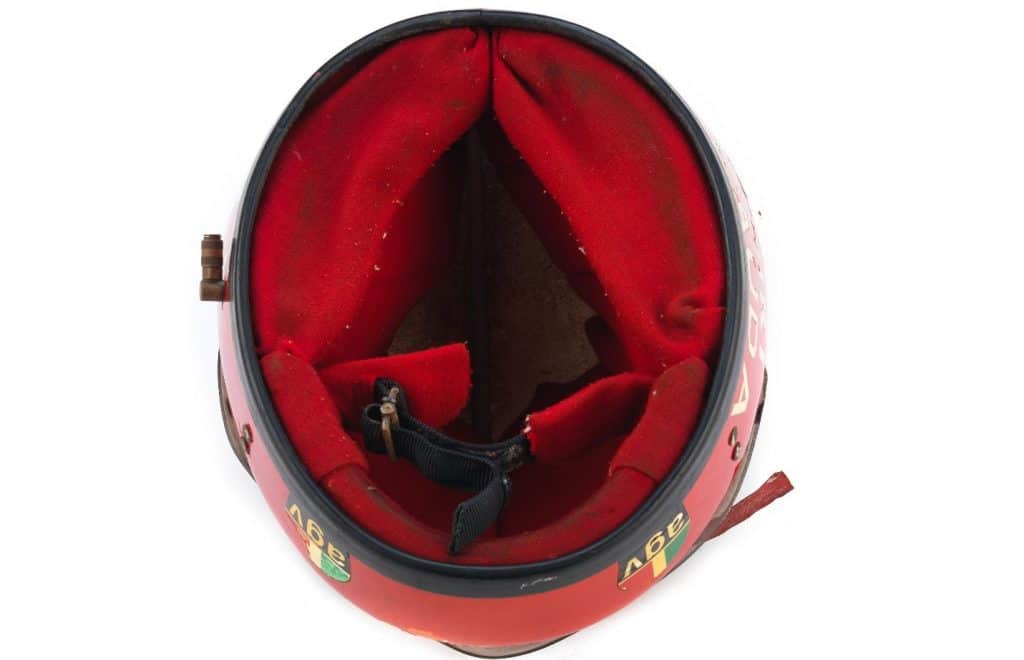 An inside view of Lauda's damaged helmet showing red cloth lining with padding, secured by a Velcro strap and buckle