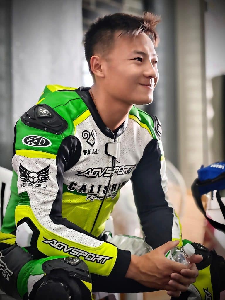 Aden Thao sits ready in a bright green-and-white AGVSPORT custom racing suit (2025) before the MotoGP and FIM BRIC Superbike Championship at Chang International Circuit in Buriram, Thailand. The suit is CE AAA certified, airbag-compatible, includes CE Level 2 body armor, and offers a fitment guarantee with up to a three-year warranty.