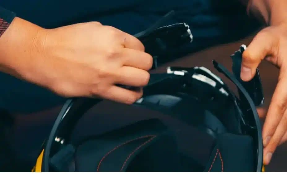 A damaged helmet being inspected for cracks and missing padding — a reminder that while visor or strap repairs are fine, any structural compromise to the shell or EPS liner means it’s time for replacement, not repair.