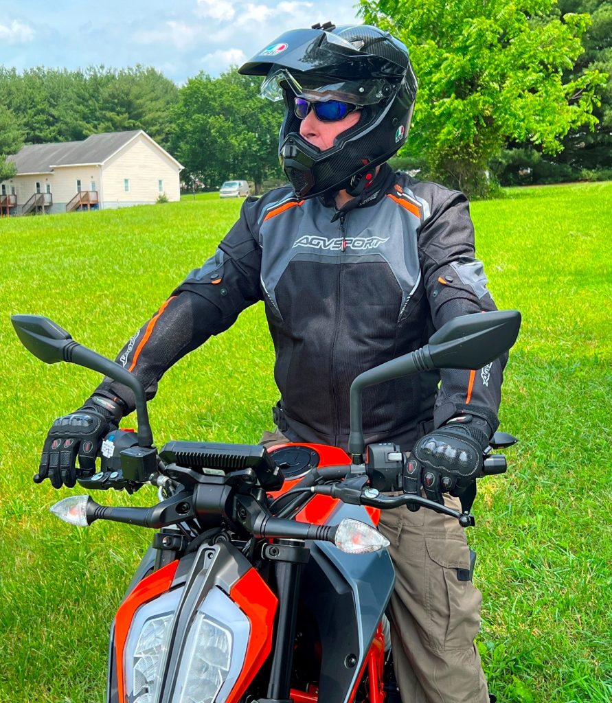 On my KTM Duke 390, a naked bike, I sit upright with a slight forward lean and my hands on wide handlebars, an agile, forward-balanced stance compared with the reclined, feet-forward, windscreen-protected posture typical of touring motorcycles.