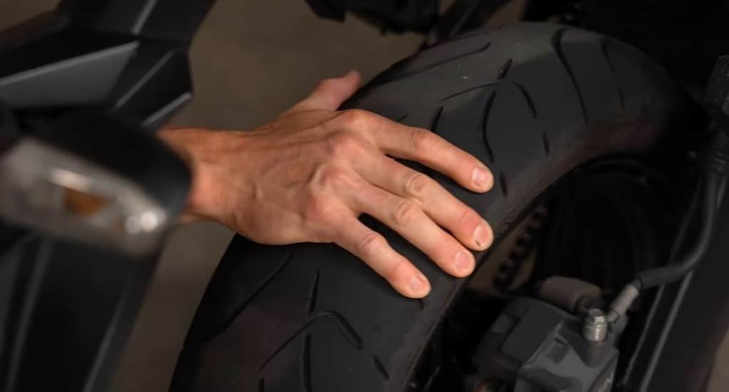 Hand rocking the rear tire of a Yamaha MT-07 to check for wheel bearing play.